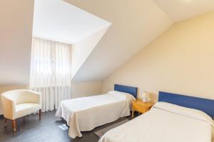 a bedroom with two beds and a chair and a window at Casa Rural Cantueso 1 in La Matilla