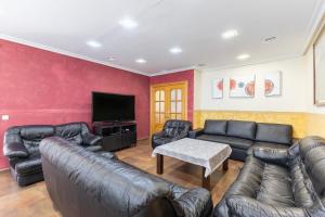 a living room with leather furniture and a flat screen tv at Casa Rural Kalfonso in Mascaraque