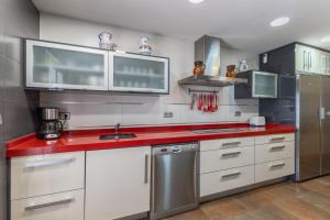 a kitchen with white cabinets and a red counter top at Casa Rural Kalfonso in Mascaraque