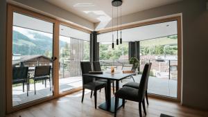 a dining room with a table and chairs and a large window at Aktiv Lodge Meran - Terrace One in San Martino +25 photos