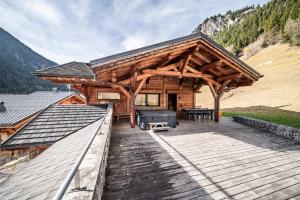 a cabin with a wooden deck with a roof at Chalet Heidi - Chatel in Châtel