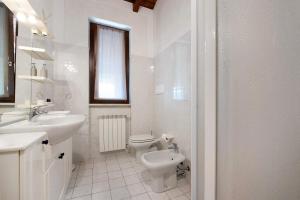 a white bathroom with a toilet and a sink at Miralago Marone Holiday House in Marone +13 photos