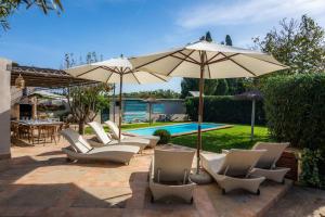 a group of chairs and an umbrella next to a pool at Es Collet in Manacor
