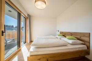 a bedroom with a wooden bed with a large window at sunnig Apartment Sonnenaufgang in Vollan