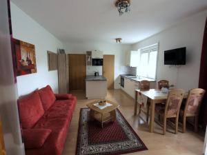 a living room with a red couch and a table at Apartment Mengelberg in Markkleeberg