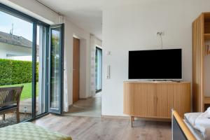 a living room with a flat screen tv on a wooden cabinet at Meili's Haus in Uhldingen-Mühlhofen