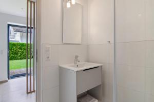a white bathroom with a sink and a mirror at Meili's Haus in Uhldingen-Mühlhofen +33 photos
