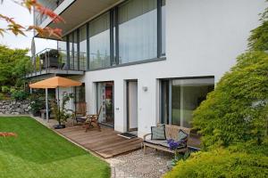 a house with a wooden deck and glass windows at Meili's Haus in Uhldingen-Mühlhofen