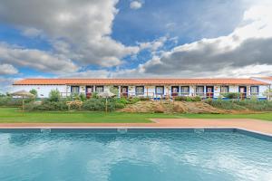 a resort with a swimming pool in front of a building at Herdade Vale de Gaios in Odemira