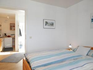 a white bedroom with a bed and a kitchen at Ferienwohnung Ketterer in Breitnau