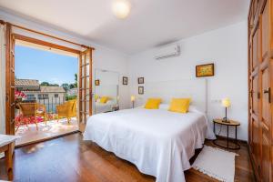 a white bedroom with a bed and a balcony at Can Toni in Pollença +33 photos