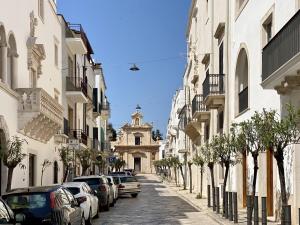 a street with parked cars and a building with a clock tower at Dimora Giulia Luxury Suite and Room in Castellana Grotte