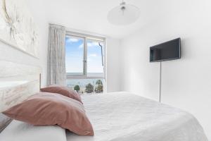a white bedroom with a bed with pillows and a television at Topete Alicante in Alicante