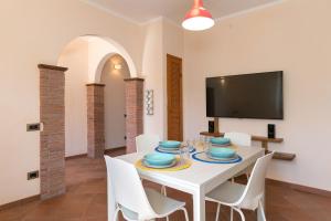 a dining room with a white table and white chairs at Al posto giusto - appartamento Sole in Riotorto