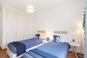two beds in a bedroom with blue sheets at Prainha Paradise - Algarve in Alvor +17 photos
