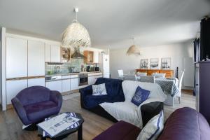 a living room with a couch and chairs and a kitchen at La Madély in Camiers
