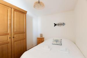 a bedroom with a white bed and a wooden cabinet at La Madély in Camiers
