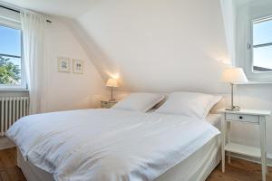 a white bedroom with a white bed and two windows at Ferienhaus Immenstaad in Immenstaad am Bodensee