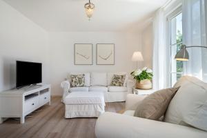 a living room with white furniture and a flat screen tv at Ferienhaus Immenstaad in Immenstaad am Bodensee