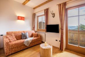 ein Wohnzimmer mit Sofa und Fernseher in der Unterkunft Oberplunerhof - Fewo Kronplatz in Kiens
