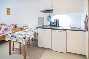 a kitchen with white cabinets and a sink and a table at Haus Ruther - Apartment in Bad Saulgau +10 photos