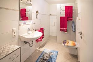 a bathroom with a sink and a toilet and red towels at Haus Ruther - Apartment in Bad Saulgau