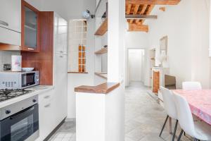 a kitchen with white cabinets and a table with white chairs at Appartamento La Naiade, Lucca in Lucca