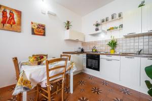 a kitchen with white cabinets and a table and a sink at Gaia Casa Vacanze in San Giovanni Suergiu