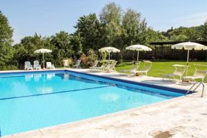 a swimming pool with chairs and umbrellas at Podere del Pereto Bio- 203 in Rapolano Terme