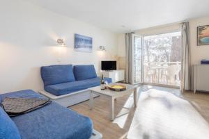 a living room with a blue couch and a table at La Cabine in Fouesnant