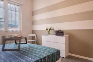 a bedroom with a striped wall with a bed and a table at Maison Bibi Lago Maggiore in Laveno-Mombello