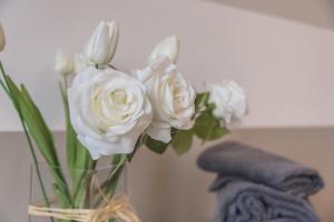 a vase filled with white roses on a table at Maison Bibi Lago Maggiore in Laveno-Mombello +12 photos