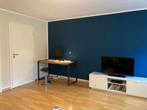 a room with a blue wall with a desk and a television at Ferienwohnung Happynest in Birresborn