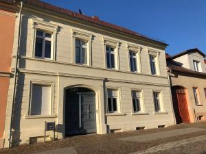 a large white building with a door on a street at Im Herzen Templins Obergeschoss in Templin
