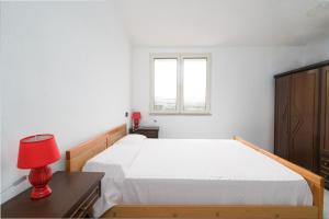 a white bedroom with a bed and a red lamp at Casa nel centro di Budoni in Budoni