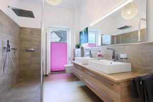 a bathroom with two sinks and a pink door at Idylisches Ferienhaus in Edewecht +32 photos