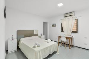 a white bedroom with a bed and a desk at Casa Mar Azul Arinaga in Arinaga