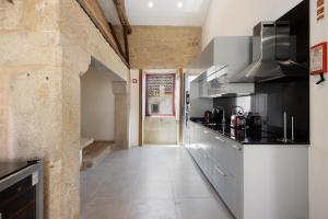 a kitchen with black and white appliances and a hallway at Villa Casa do Outeiro in Guilhabreu