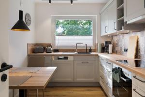 a kitchen with white cabinets and a sink and a window at Ferienhaus Anna Elbe in Wischhafen