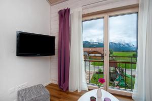 a living room with a tv and a large window at Ferienwohnung Junge in Halblech