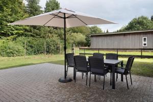 a table with chairs and an umbrella on a patio at Ferienhaus Anna Elbe in Wischhafen