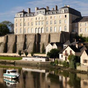 a boat in the water in front of a large building at Pause Tranquille - Chambres d'hôtes in Sablé-sur-Sarthe