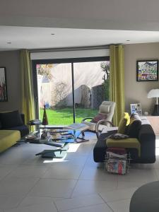 a living room with couches and a large window at Pause Tranquille - Chambres d'hôtes in Sablé-sur-Sarthe