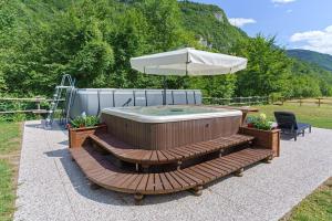 a hot tub sitting on a wooden bench with an umbrella at Chalet Camillo in Moline