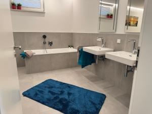 a bathroom with two sinks and a tub and a blue rug at Berg und Meer in WÃ¶lpinghausen +20 photos