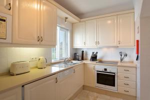 a kitchen with white cabinets and a sink at Vila Senna in Vale do Lobo