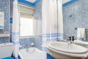 a blue and white bathroom with a tub and a sink at Apartamento Oliva in Barbate +21 photos