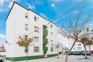 a white building with green windows on a street at Apartamento Oliva in Barbate