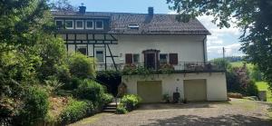 a large white house with two garage doors at Landhauswohnung Alte Mühle in Berlinghausen