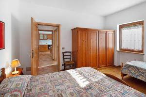 a bedroom with a bed and a cabinet and a chair at Residence Malibu Appartamento 3 in Falcade